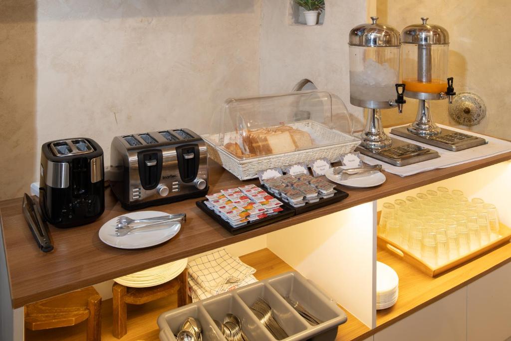 A self-service breakfast counter with toasters, bread, spreads, and drinks.