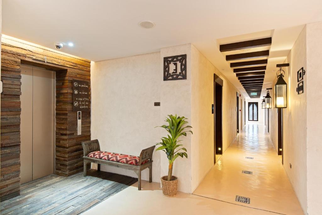 A bright hotel corridor with a small upholstered bench beside the elevator.