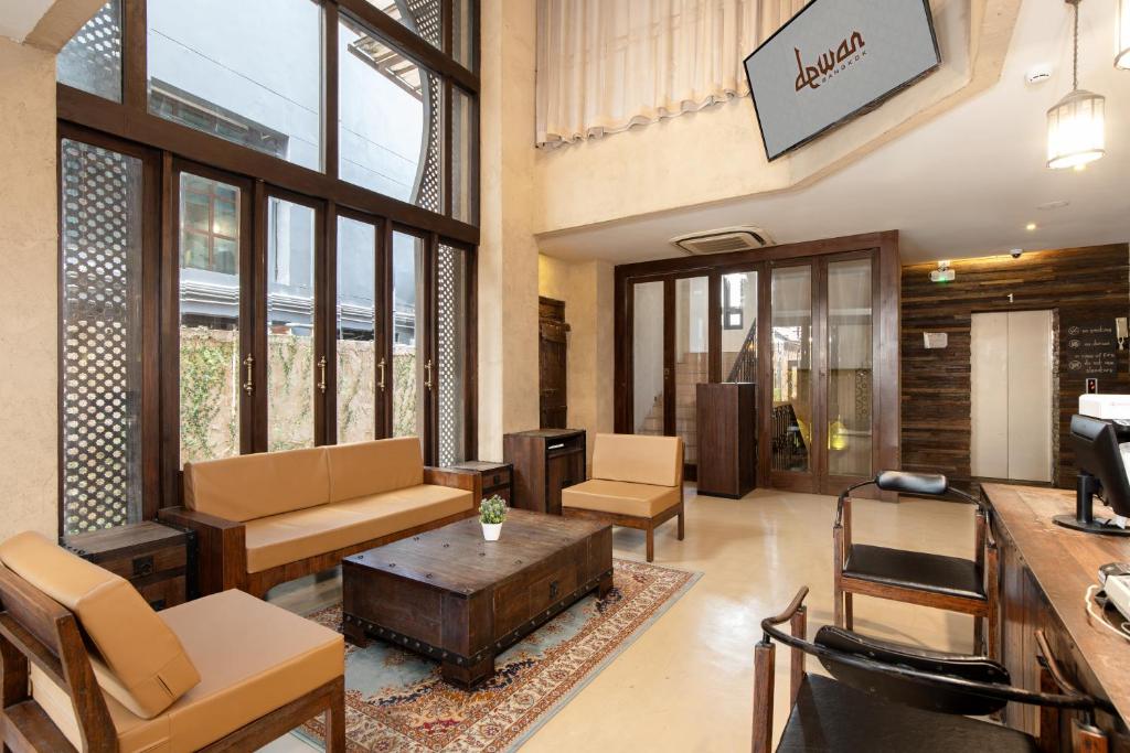 A bright hotel lobby lounge with sofas, armchairs, and a reception counter.