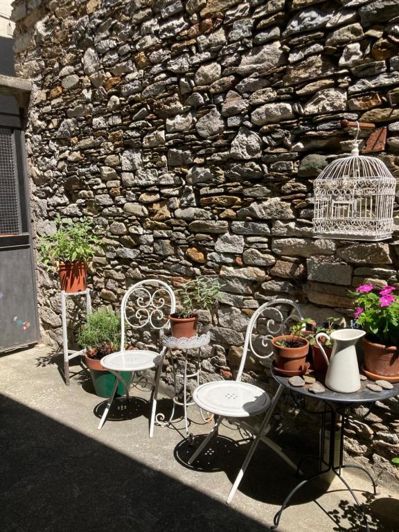 2 Stühle und ein Tisch vor einer Steinmauer in der Unterkunft La casina del lago vicino al bosco in Ghiffa