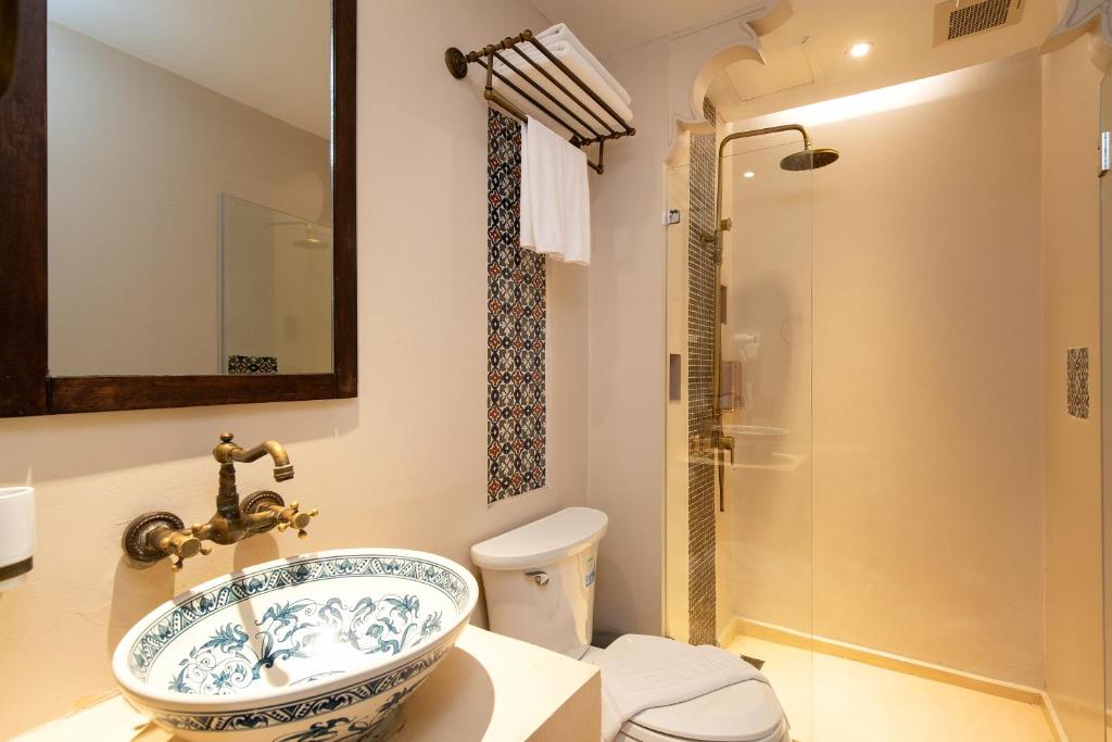 A compact bathroom with a patterned basin and glass-enclosed rain shower.