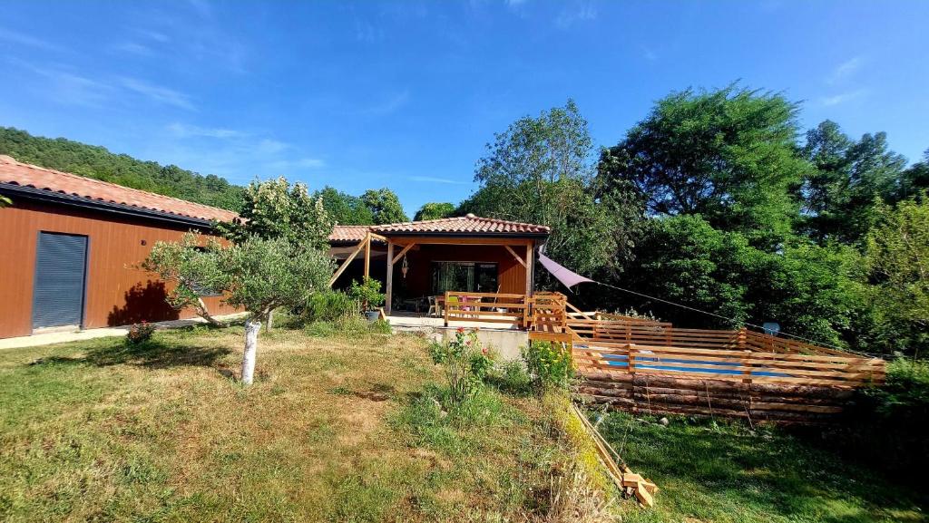 une maison avec une clôture en bois devant elle dans l'établissement Maison et piscine bien située en sud ardeche très grand jardin, à Saint-Paul-le-Jeune