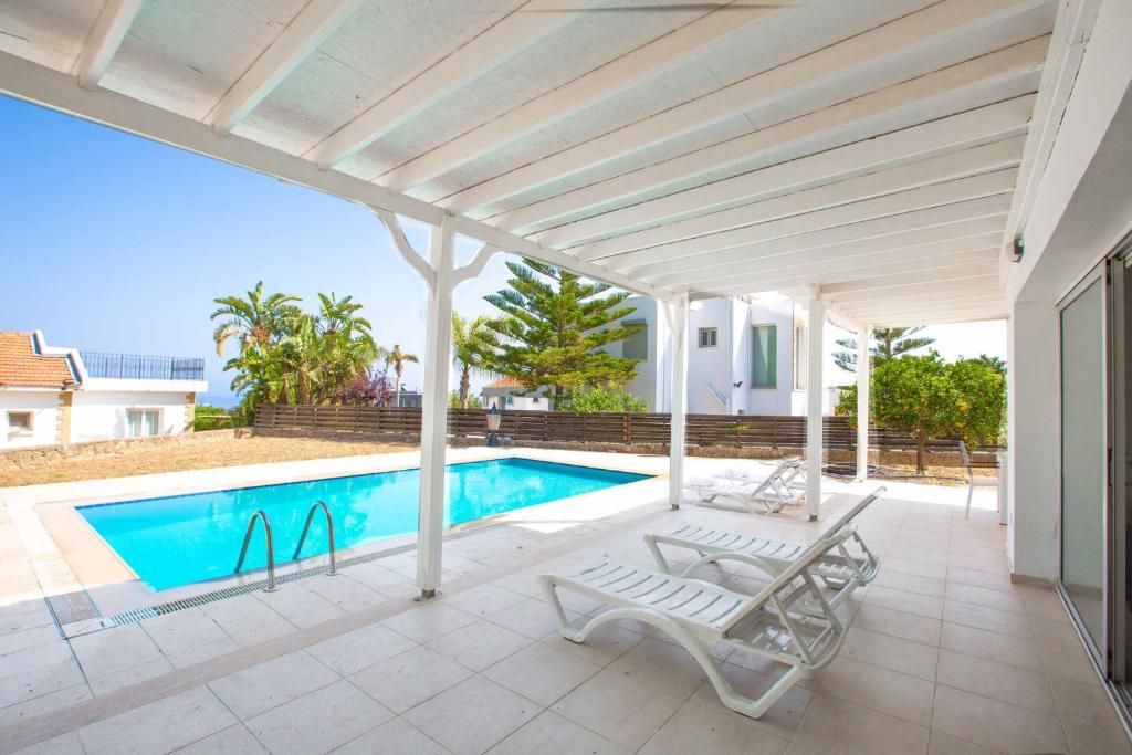 a patio with a pool and two chairs next to a house at Bitter Orange Villa with Pool by HolidayKeys in Kyrenia