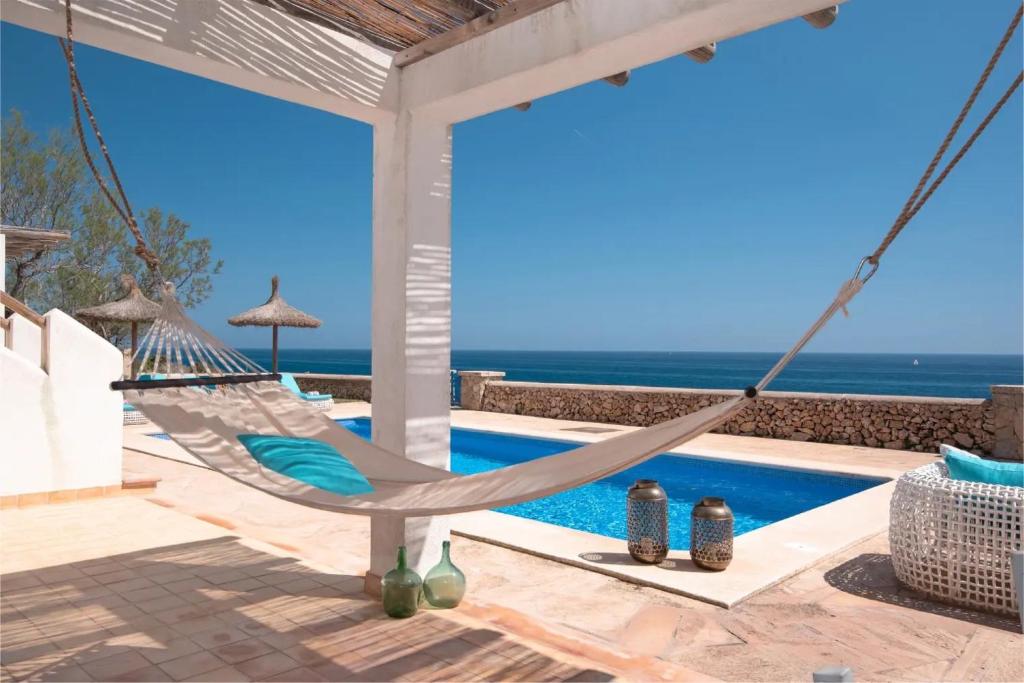 a hammock on a patio next to a swimming pool at Villa Domus Alba B in Portocolom