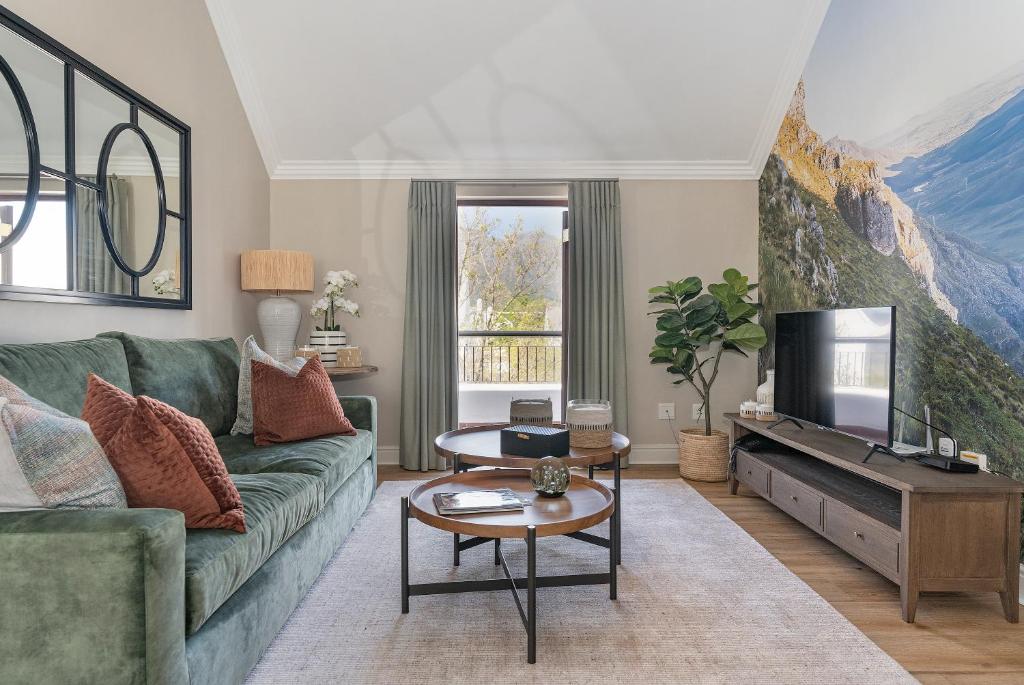 a living room with a green couch and a tv at Winelands Golf Lodges 39 in Stellenbosch