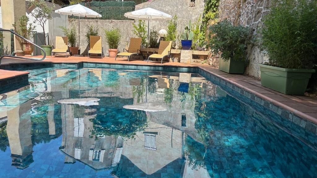 una piscina con sillas y sombrillas en Logis Hôtel Restaurant Grand Hôtel de Lyon, en Vals-les-Bains