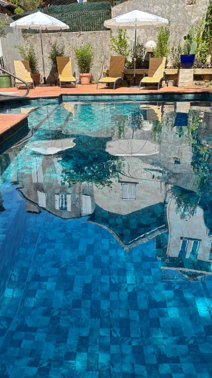 une piscine à l'eau bleue avec chaises et parasols dans l'établissement Logis Hôtel Restaurant Grand Hôtel de Lyon, à Vals-les-Bains