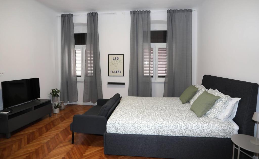 a bedroom with a bed and a couch and a television at Nona Marija Centar Apartments in Pula