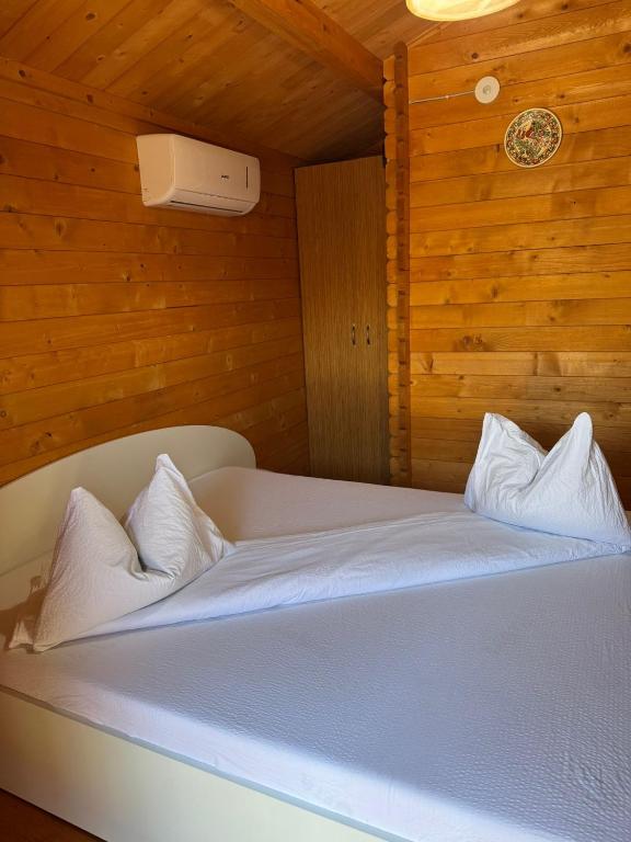 a white bed in a room with wooden walls at Casute Enea Baile Figa cu Aer condiționat in Agrişu de Sus