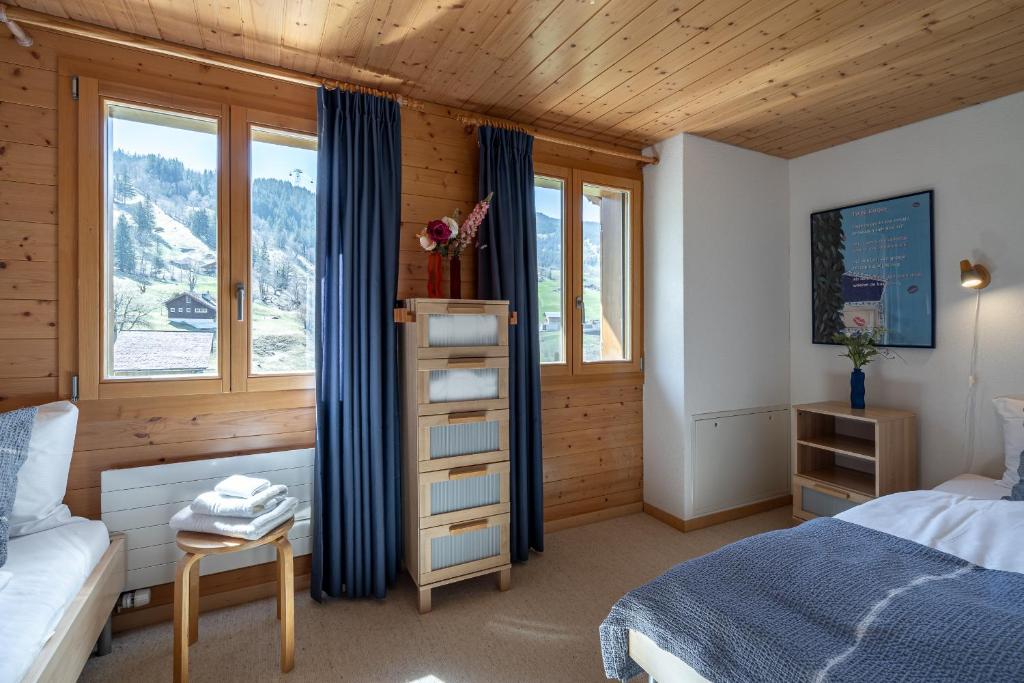 a bedroom with a bed and a desk and windows at Chalet Studen in Grindelwald