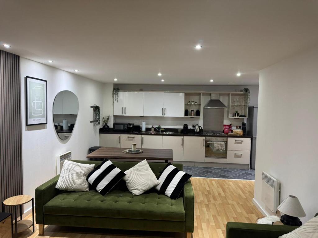 a living room with a green couch and a kitchen at Modern 2BR Apartment City Centre Free Secure Parking Stunning Views in Birmingham