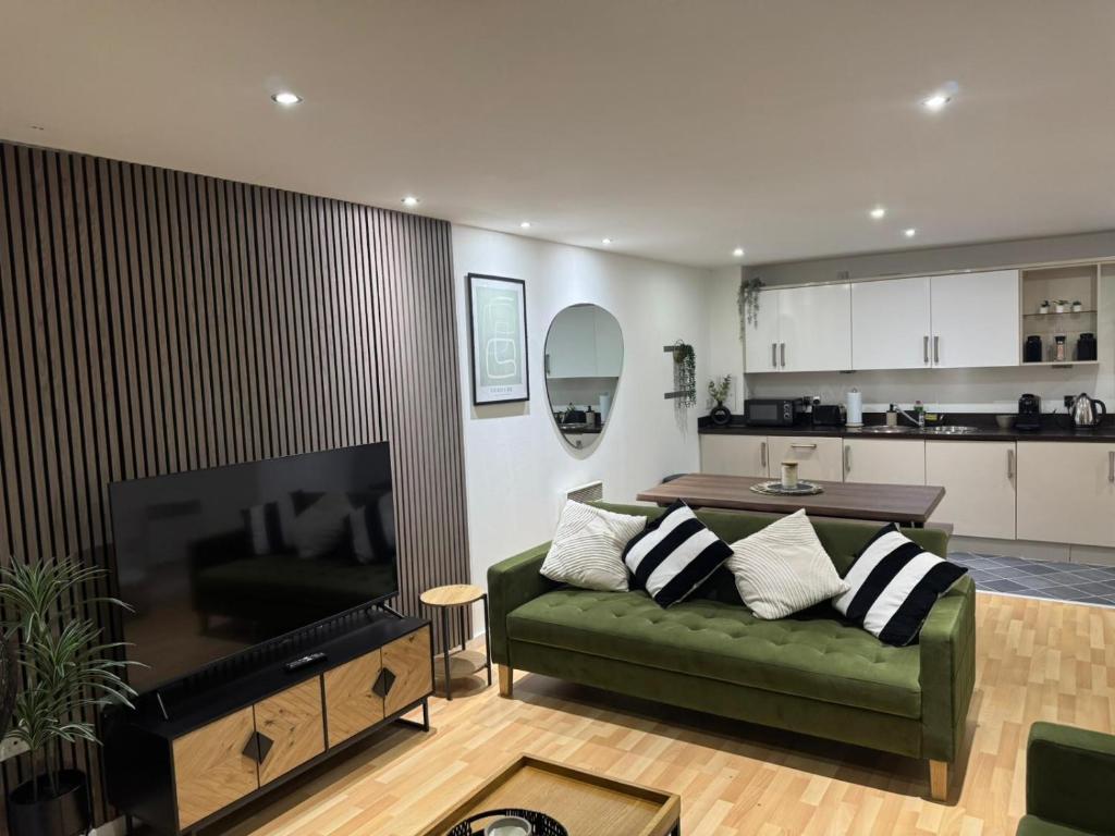 ein Wohnzimmer mit einer grünen Couch und einer Küche in der Unterkunft Elegant TWO Bedroom Apartment Amazing Views Birmingham City Centre FREE Underground Parking in Birmingham