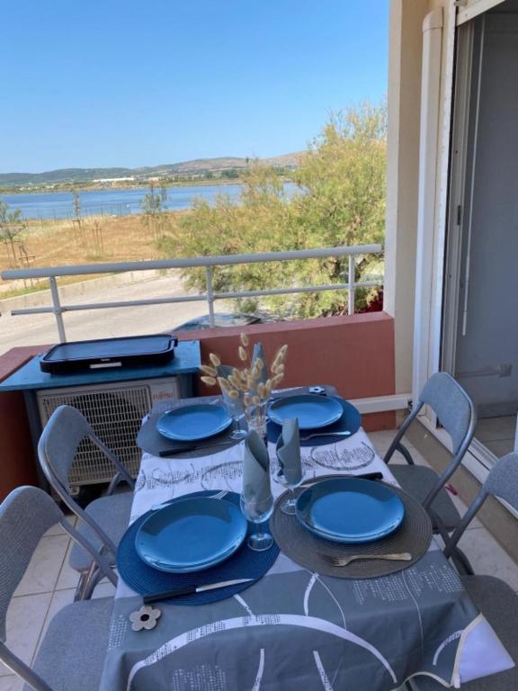 une table avec des assiettes bleues et des chaises sur un balcon dans l'établissement comfort and breathtaking view, à Frontignan