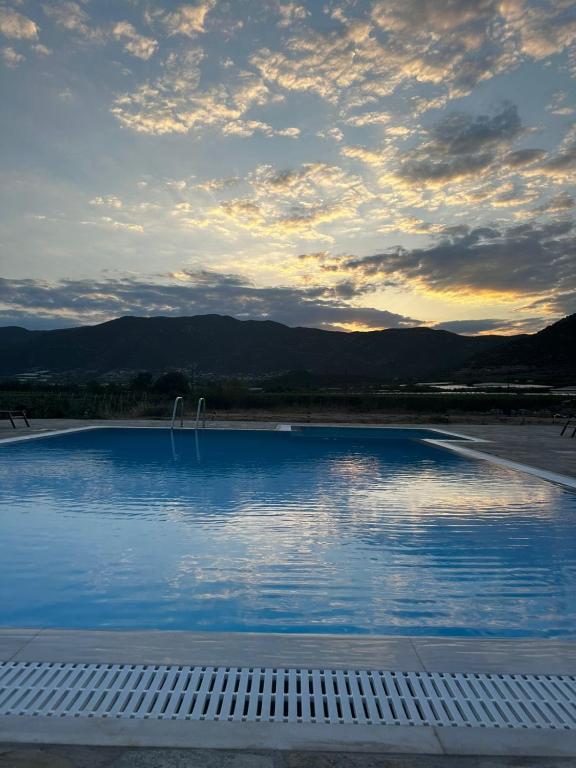 a large swimming pool with a cloudy sky above it at Petra Nova Suites in Nea Peramos
