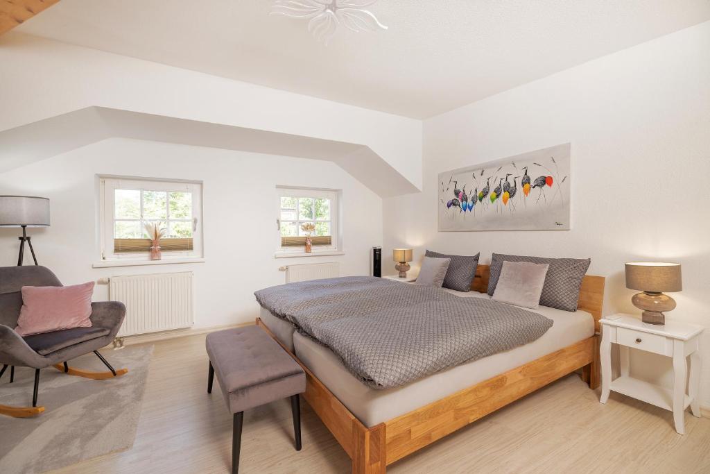 a bedroom with a large bed and a chair at Haus mit 110qm und Garten 150m zum Wasser in Stralsund