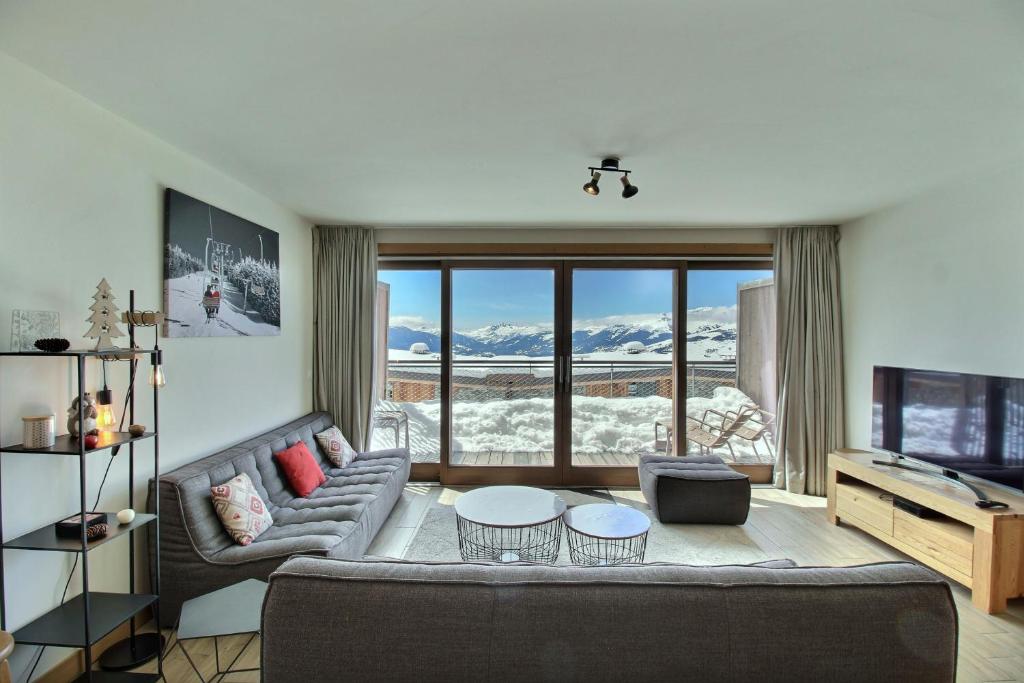 a living room with a couch and a large window at ARC 1600, LE RIDGE, Appartement 10 personnes Duplex Vue Montagne - ski aux pieds - Sauna, Hammam, Piscine, Salle de salle de sport-fitness in Arc 1600