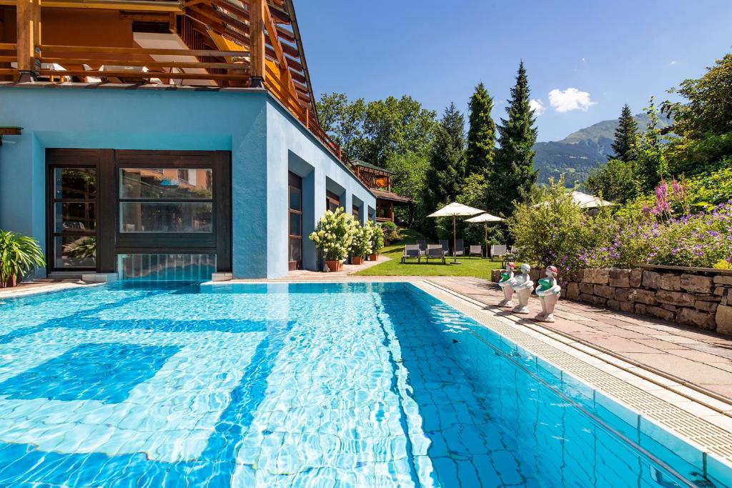 two children standing next to a swimming pool next to a house at Geniesserhotel Montafoner Hof in Tschagguns