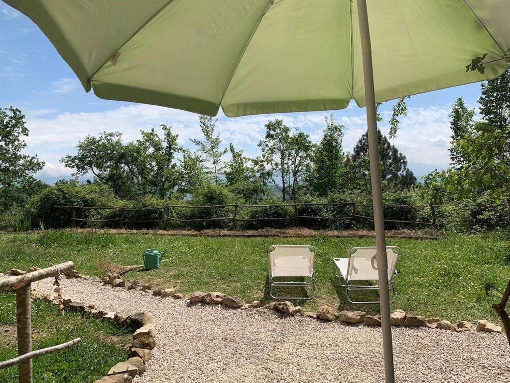 two chairs sitting under an umbrella in a yard at Ina Maka - Appartamento con giardino immerso nel verde in Mengara
