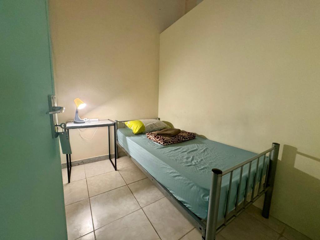 a small bedroom with a bed and a side table at Backpacker's Bed - No Parking in Abu Dhabi