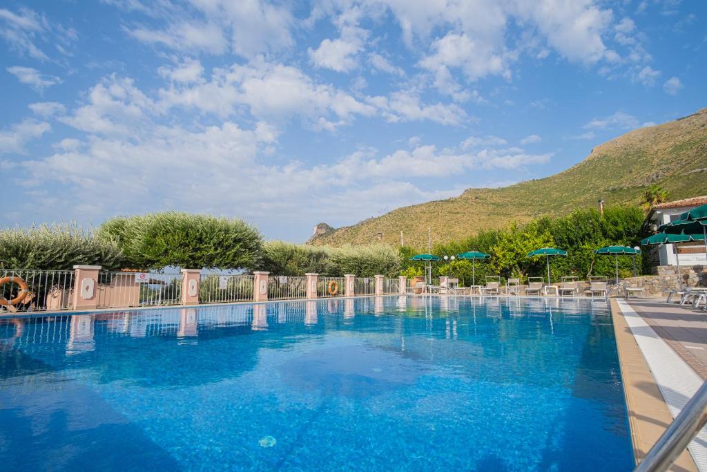 a large blue swimming pool with chairs and umbrellas at Hotel Ristorante Borgo La Tana in Maratea