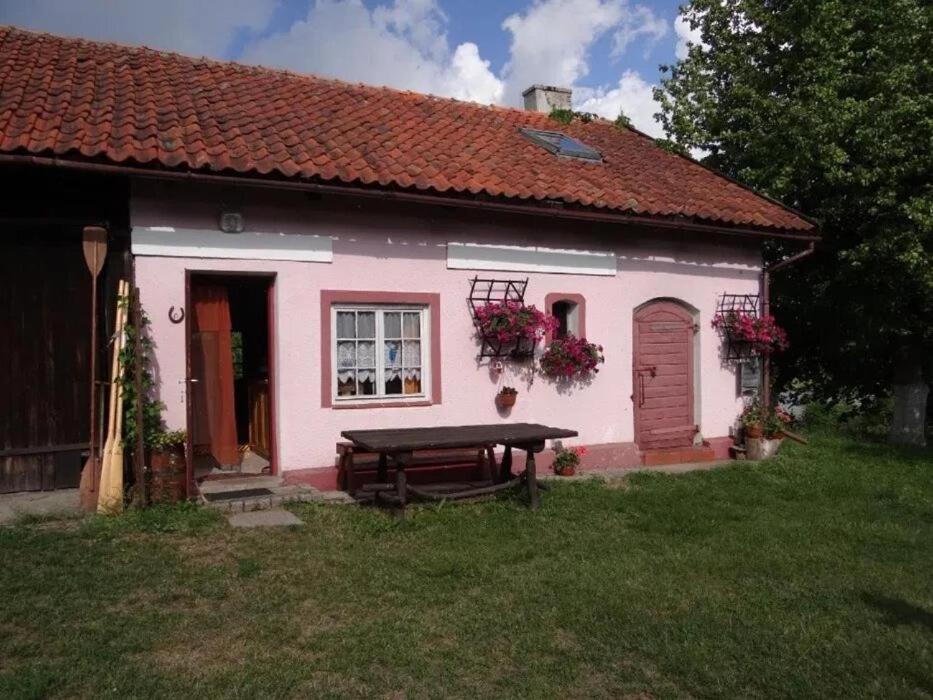 a pink house with a picnic table in front of it at Agroturystyka Oczko in Ogonki