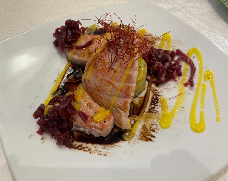 a white plate of food with meat and grapes at Hotel Ristorante Borgo La Tana in Maratea