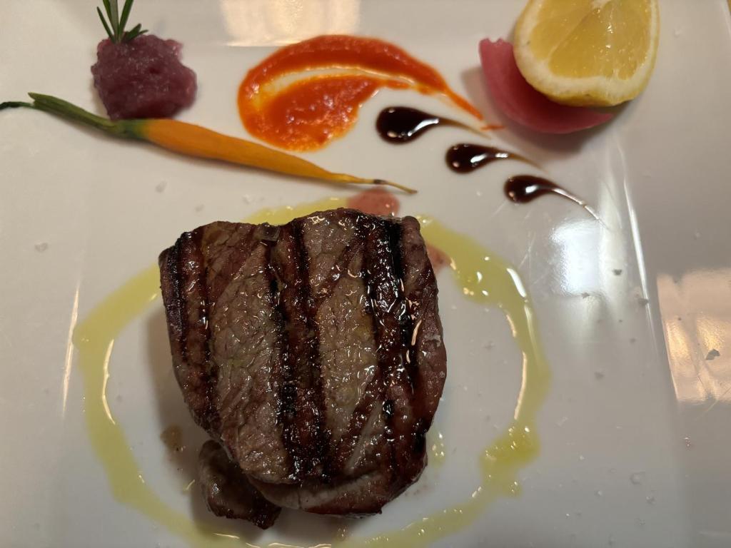 a piece of steak on a white plate with fruit at Hotel Ristorante Borgo La Tana in Maratea