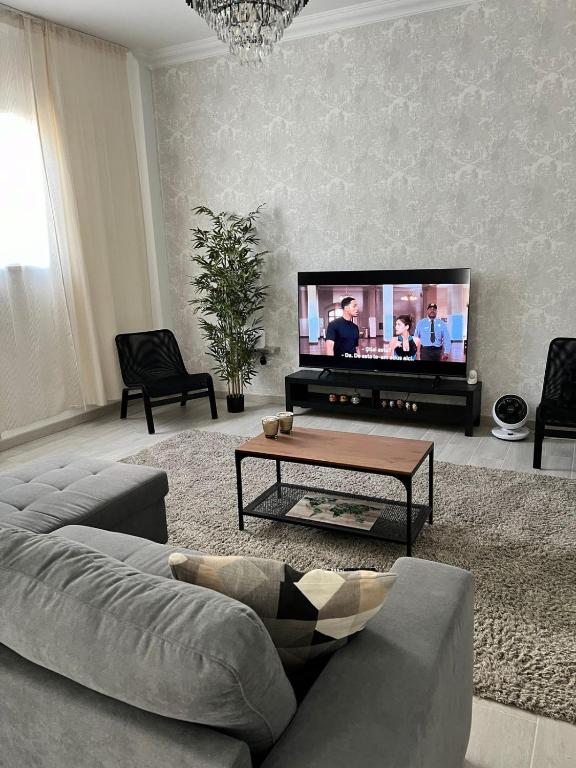 a living room with a couch and a flat screen tv at The Pearl Suite - your stylish cozy and modern flat,in the heart of South Tenerife,just 3 minutes from beach and natural pools in Alcalá