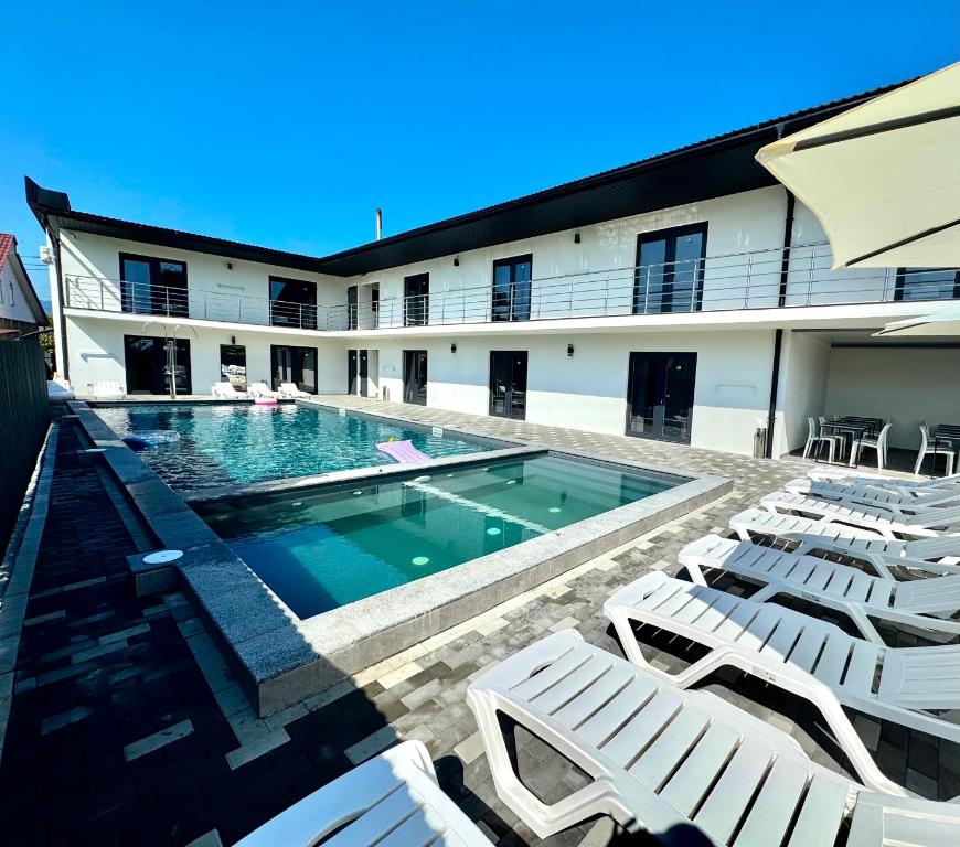 a swimming pool with white lounge chairs next to a building at Hotel Elena Solotvino in Solotvyno