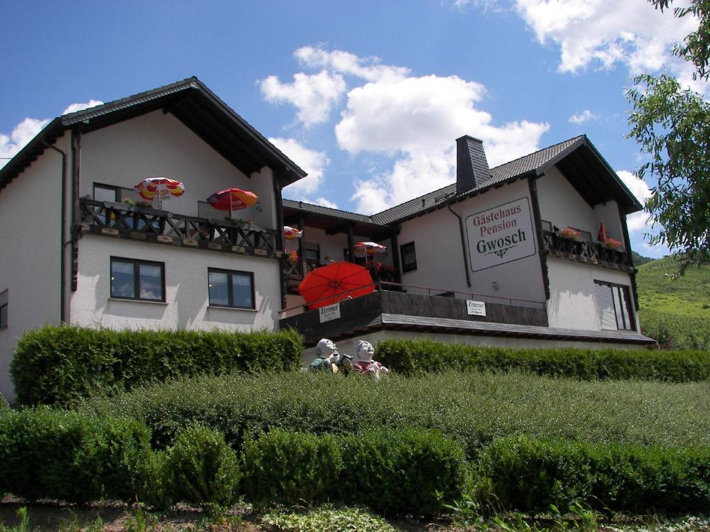 ein Gebäude mit einem Balkon mit roten Sonnenschirmen darauf in der Unterkunft Ferienwohnung Moselpension Gwosch in Bruttig-Fankel