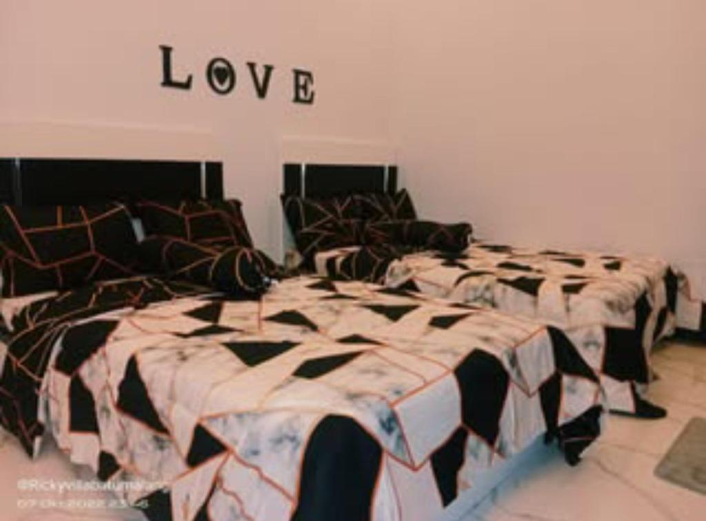 two beds in a room with love sign above them at Oemah Sawah99 in Batu
