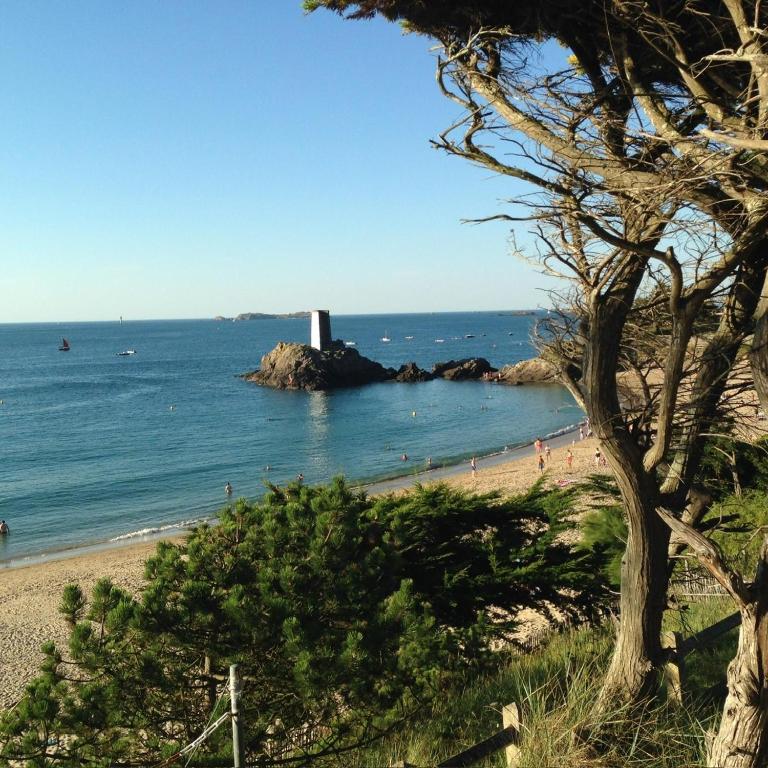 a group of people on a beach with a lighthouse at Villa Les Charmettes in Saint-Lunaire