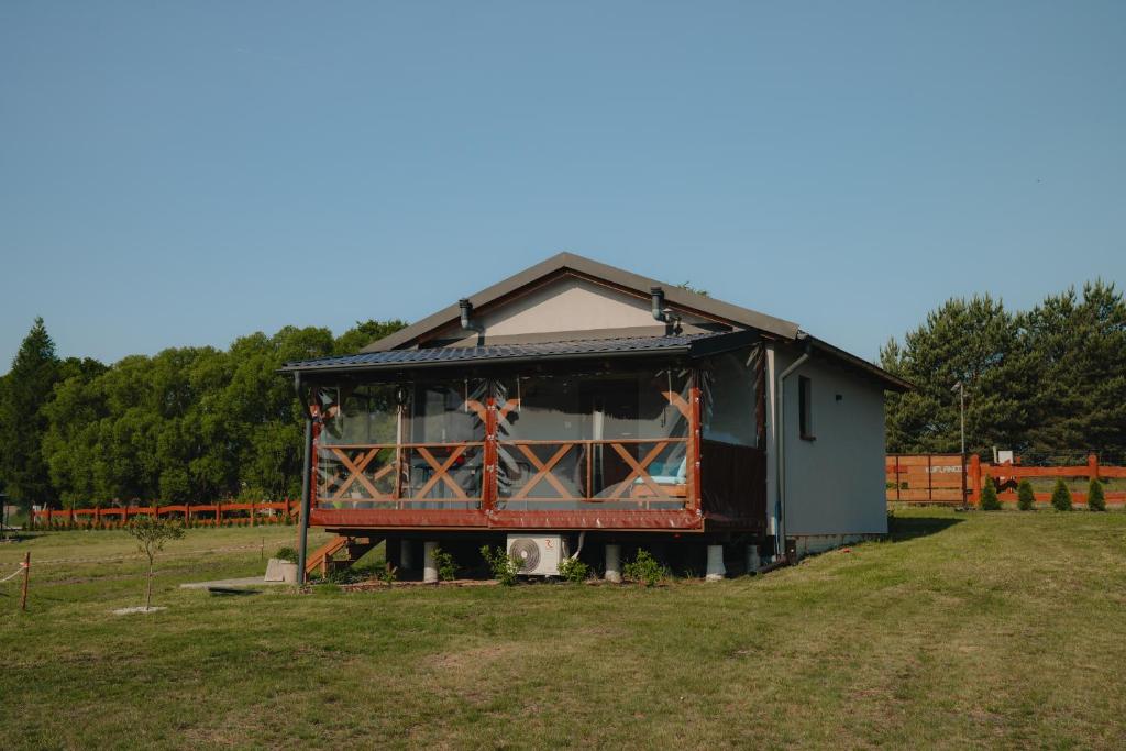 a small building with a fence in a field at Ranczo KUFLANDIA Średnia Huta in Średnia Huta