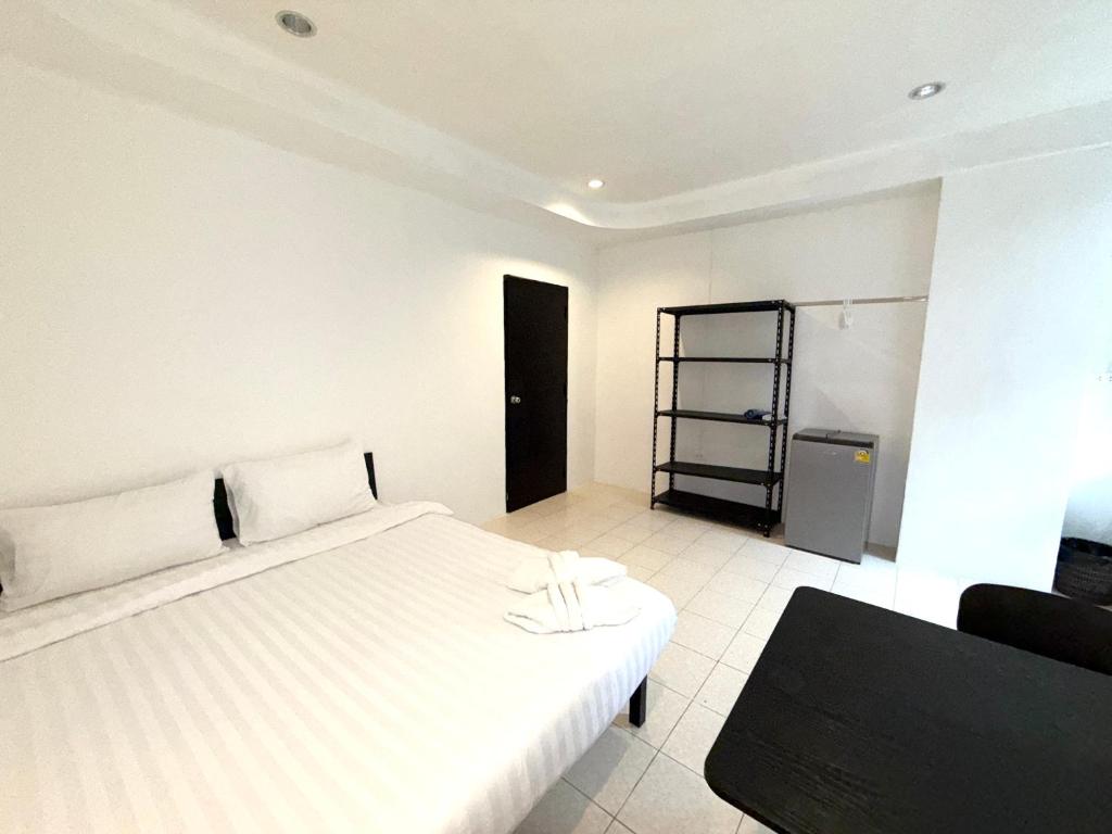 a bedroom with a white bed and a black chair at Patong Canal Villa R105 in Patong Beach