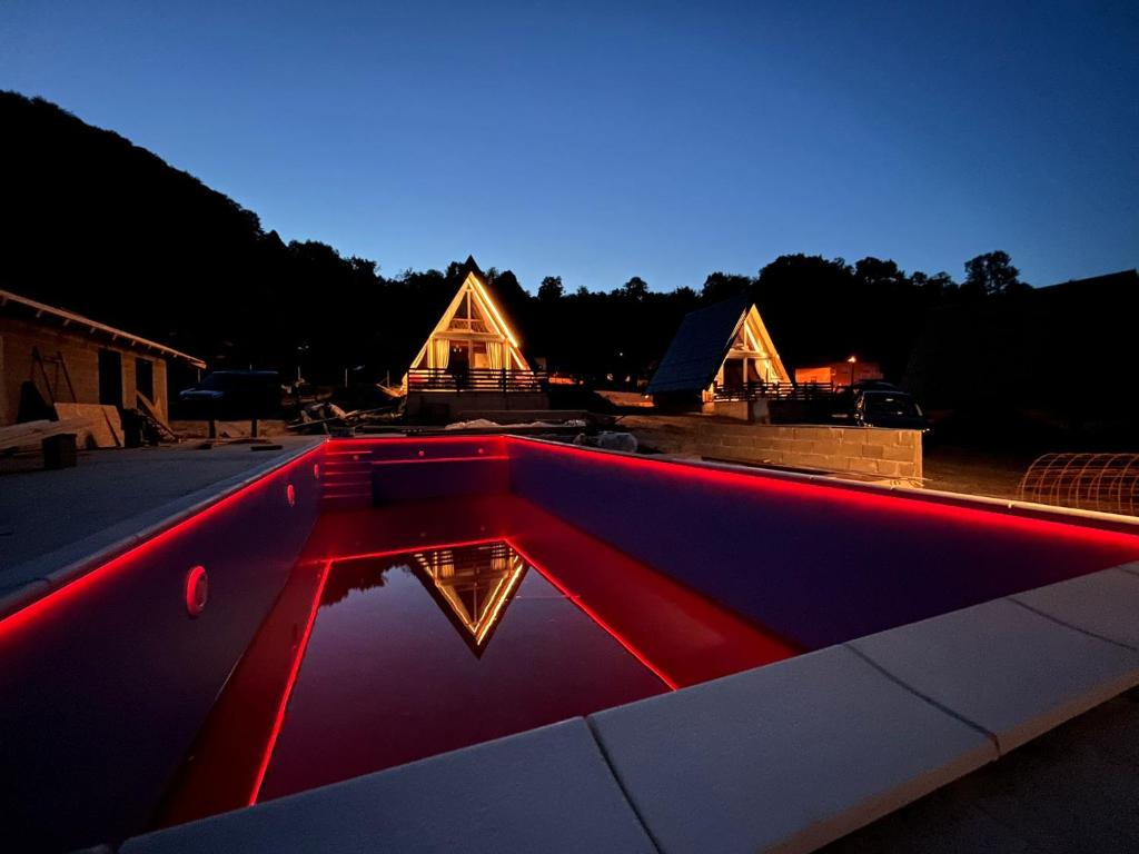 a swimming pool with a house in the background at JAGI Bungalovi Mrkonjic Grad in Mrkonjić Grad