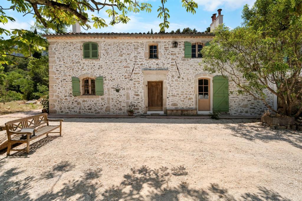 une maison en pierre avec un banc devant elle dans l'établissement Joli gîte dans les collines, à Toulon