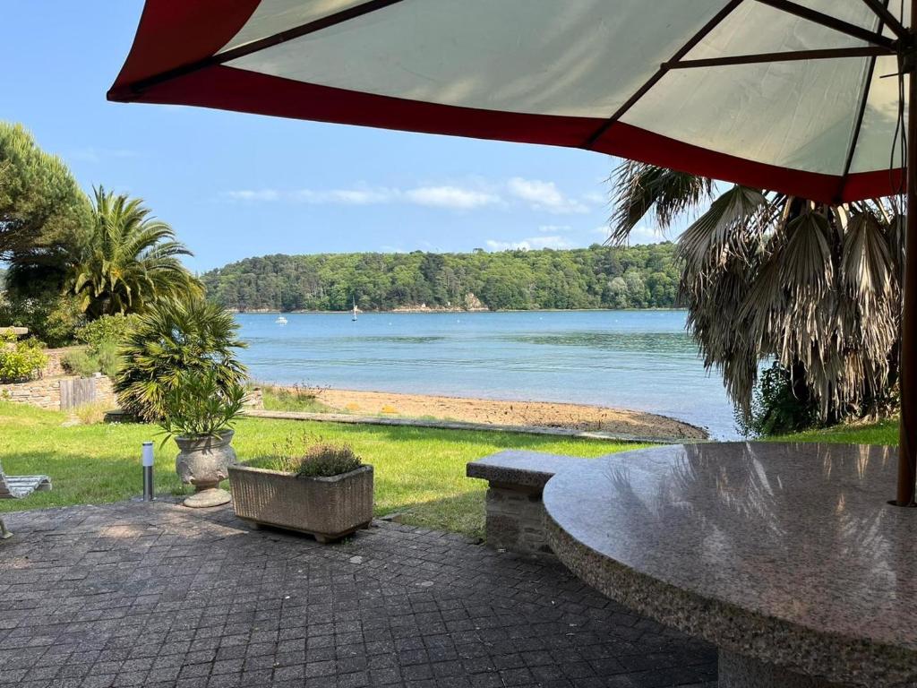 a table with an umbrella and a view of the water at Rivage secret in Lézardrieux