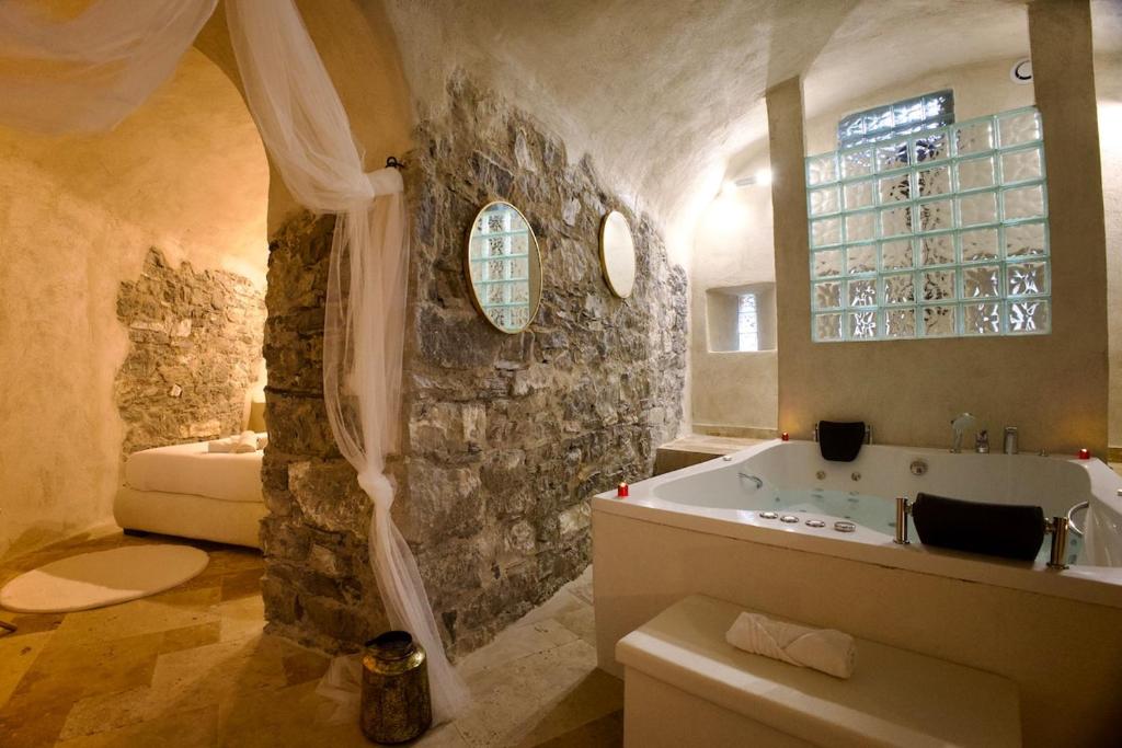 a bathroom with a tub and a stone wall at Love Room du Château Fort - Jacuzzi & Insolite ! in Mercury