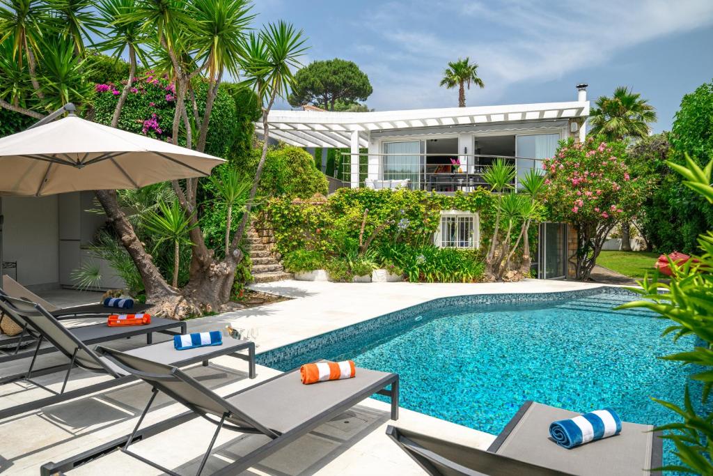 une piscine avec des chaises et un parasol ainsi qu'une maison dans l'établissement CANNES VILLA: 15 mins walk to beach & centre, à Cannes