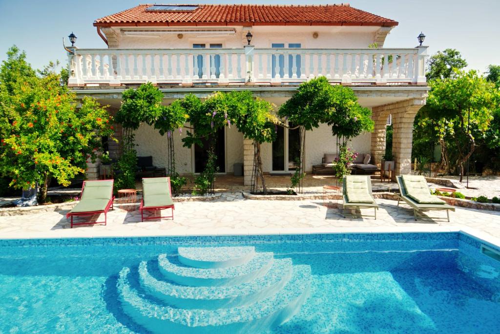 a house with a swimming pool in front of a house at Villa Vika Apartments in Njivice