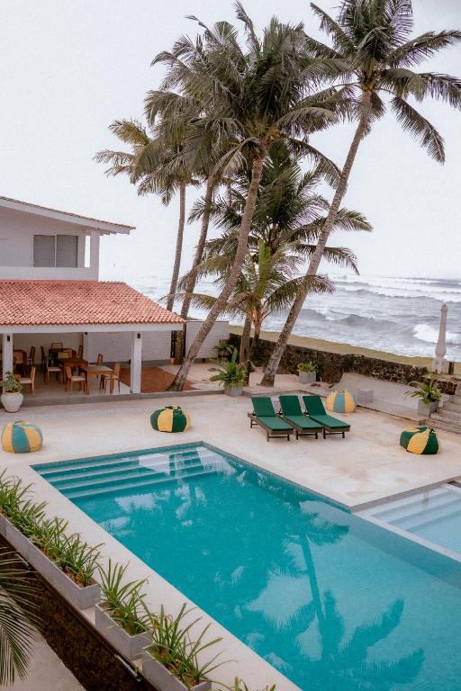 コッガラにあるThe South Beach - Ahangamaのヤシの木と海のスイミングプール