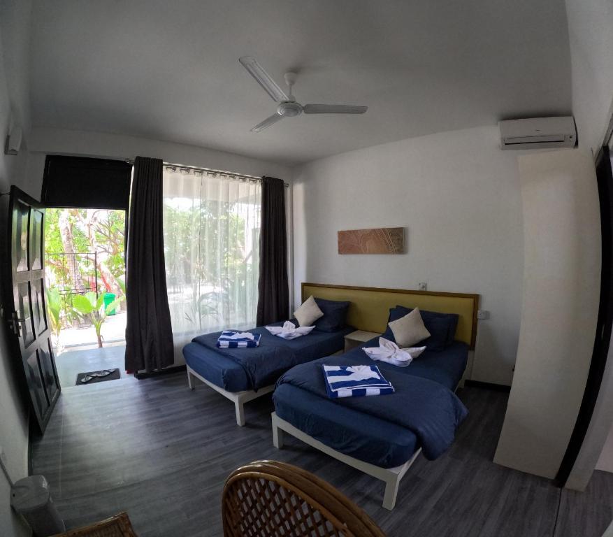 a hotel room with two beds and a window at Adroit Sunset View in Guraidhoo