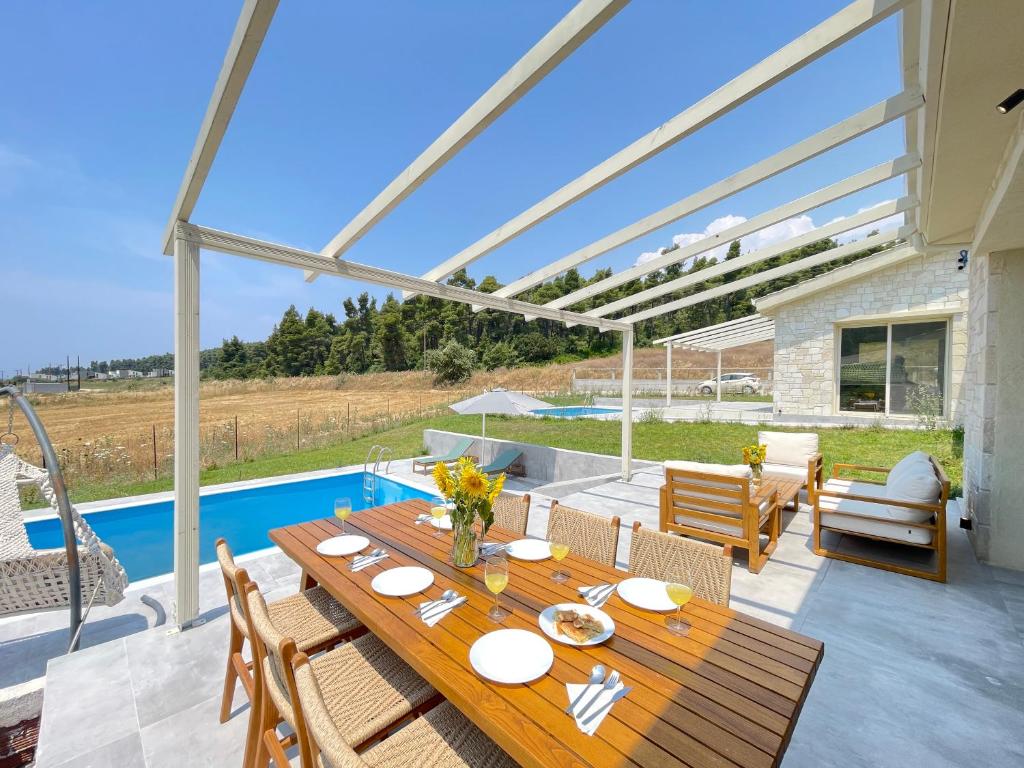 un patio avec une table en bois et une piscine dans l'établissement Villa Anastasia, à Elani