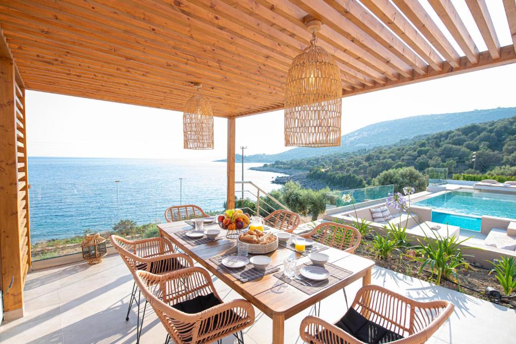 a dining table on a patio with a view of the ocean at Lefkira Seafront Villa in Évyiros
