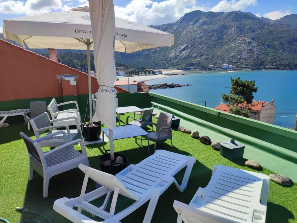 un gruppo di sedie e un ombrellone su un tetto di Villa T de Pescadores a Dumbría
