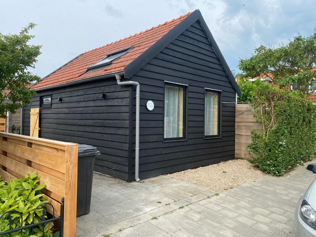 a black house with a red roof at NoSa Sleep, Sfeervol vakantiehuis in Grijpskerke in Grijpskerke