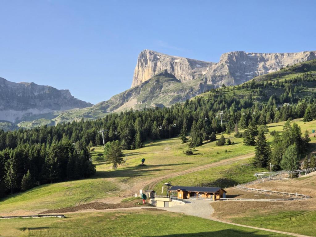 - une vue sur la montagne avec un bâtiment dans un champ dans l'établissement Appt pied pistes et centre station Superdévoluy chez Locasoleil, à Saint-Étienne-en-Dévoluy