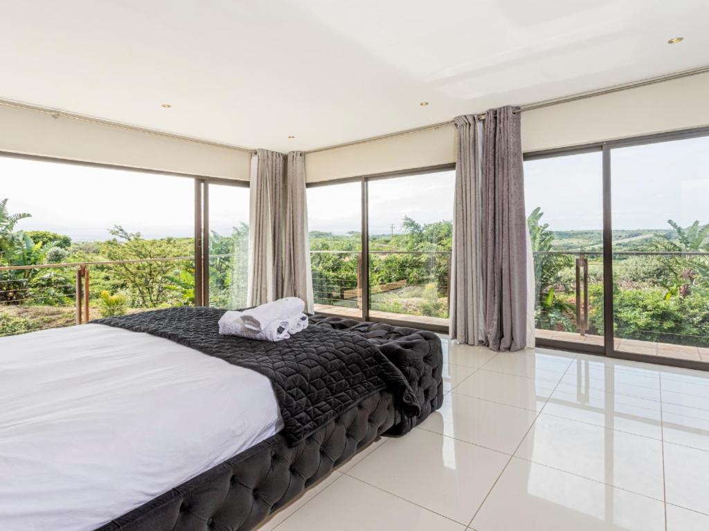 a bedroom with a large bed and large windows at Corals 4, Zimbali Estate by Euphoric Leisure in Ballito