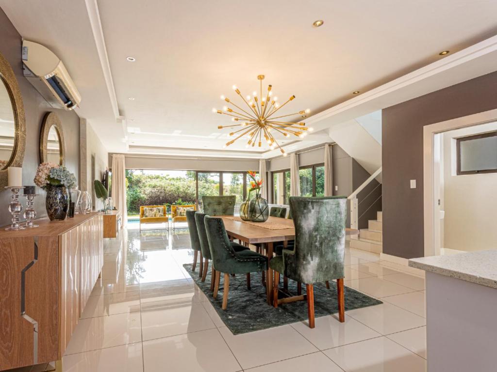 a dining room with a table and chairs and a chandelier at Corals 4, Zimbali Estate by Euphoric Leisure in Ballito