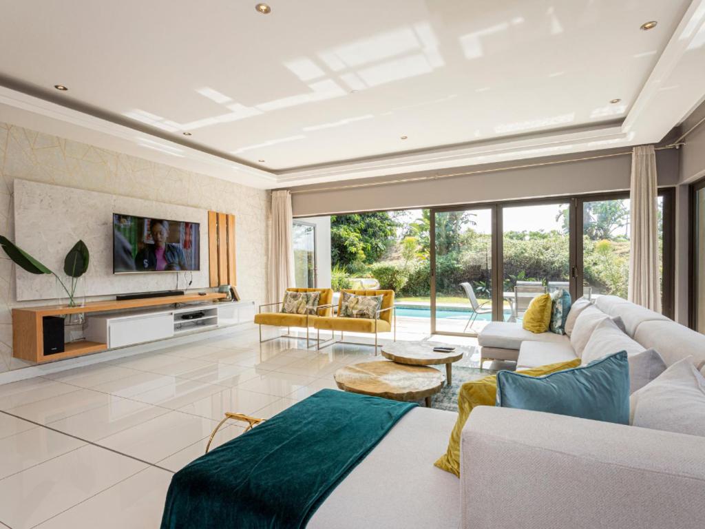 a living room with a white couch and a tv at Corals 4, Zimbali Estate by Euphoric Leisure in Ballito